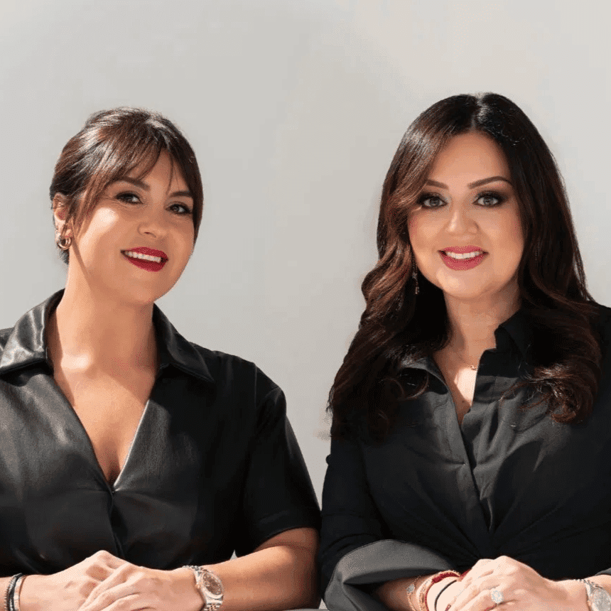 Two women smiling under a "Rêve Salon" sign, both in black outfits.